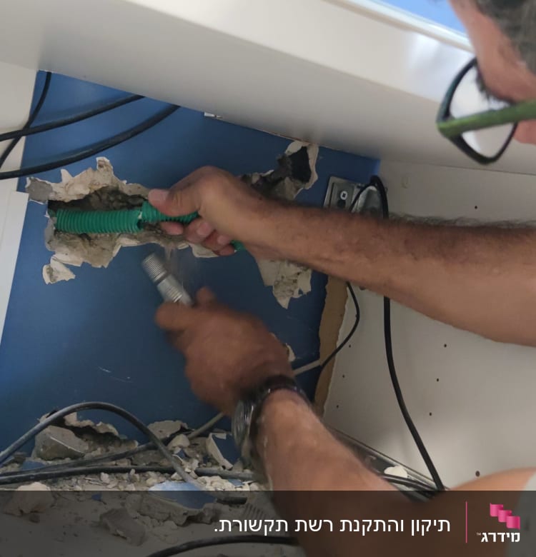 טכנאי רשתות עובד עם כבלים בתוך קיר